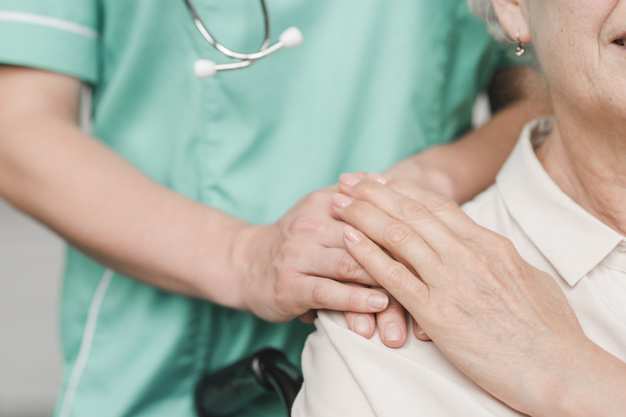 senior woman patient touching female nurse hand shoulder